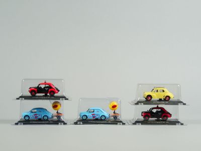 Plusieurs petites voitures sont exposées dans une vitrine posée sur une surface blanche