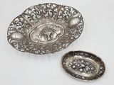 two silver dishes and a silver spoon on a white surface