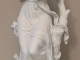 une statue représentant une femme tenant un oiseau, posée sur un socle