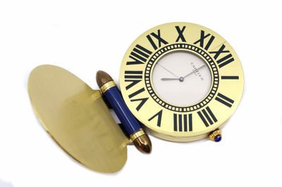 une horloge avec des chiffres romains et un stylo posé devant