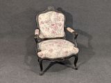 une petite chaise dont le dossier et les accoudoirs sont recouverts d'un tissu à motifs floraux