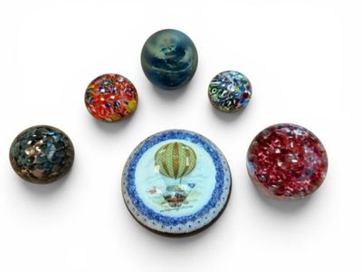 five different colored marbles on a white surface