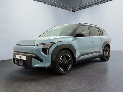 a blue car is parked in a large room with a white wall