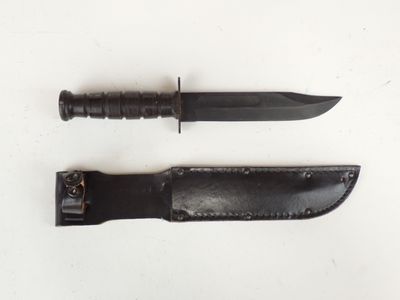 pair of knives on a white surface with a leather sheath