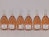 six bouteilles de vin rosé alignées sur une surface blanche