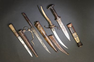 Plusieurs types de couteaux sont exposés sur un fond noir