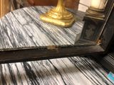 a mirror on a table with a gold candle on it