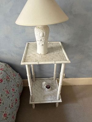 a white table with a lamp on it next to a bed