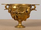 a gold vase with a bird on it on a table