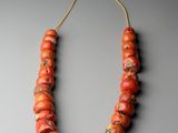un gros plan d'un collier composé de perles orange sur un fond gris
