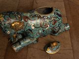 a blue elephant figurine sitting on the floor next to a small gold object
