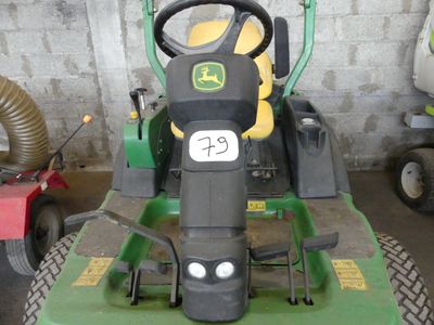 a green tractor parked in a garage with a hose attached to it