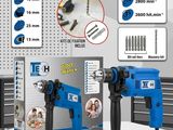 deux perceuses électriques posées sur une table, à côté d'une boîte de vis
