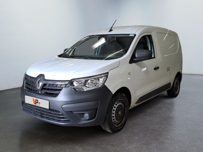 La camionnette blanche est garée dans une grande pièce au sol noir.
