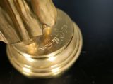 a gold statue of a woman holding a gold umbrella