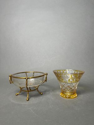 two glass bowls with gold rims and handles on a gray surface