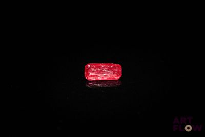 un diamant rouge sur une surface noire dans l'obscurité
