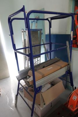 une photo d'une plate-forme de travail dans une pièce où se trouvent des cartons et des outils