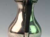 a silver pitcher with a black handle on a table