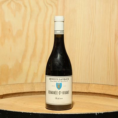 a bottle of wine sitting on top of a barrel