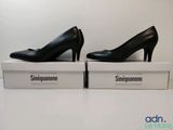 une paire de chaussures noires à talons hauts posée sur une boîte blanche