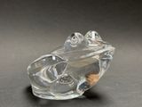 clear glass figurine of a frog on a black surface