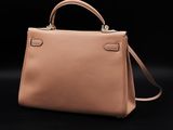 a beige leather handbag on a black background