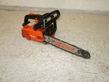 an orange and black chainsaw sitting on the floor next to a white wall