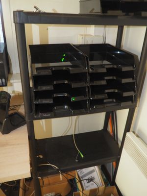 une étagère noire sur laquelle sont posés plusieurs bacs noirs