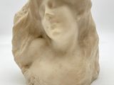 sculpture représentant la tête d'une femme sur un rocher, sur fond blanc