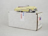 une petite voiture jaune posée sur une boîte en carton, sur une surface blanche