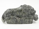 statue of a lion resting on a rock on a white background