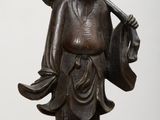statue représentant un homme tenant un sac, posée sur un socle en bois