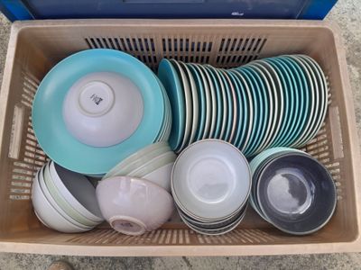 de nombreuses assiettes et bols dans un panier posé par terre