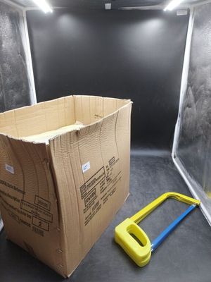 une boîte en carton avec une poignée jaune à côté d'une scie