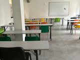 many tables and chairs in a room with a whiteboard on the wall