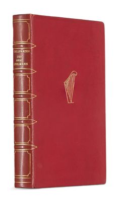 un livre rouge aux bords dorés, avec une harpe sur la couverture