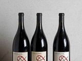 three bottles of wine sitting on top of a wooden table
