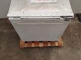 a white refrigerator sitting on a pallet in a room