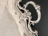 an antique silver plate with ornate design on a black background