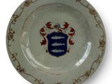 a white plate with a blue and red coat of arms on it