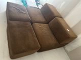 a brown couch sitting on top of a white floor next to a window