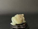 carved jade figurine of a snail on a rock on a black surface