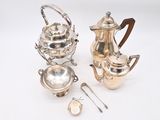 two silver teapots, a teapot and a spoon on a white surface