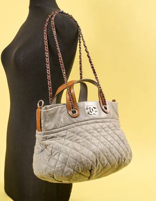 une femme tenant un sac à main gris, posée sur un mannequin