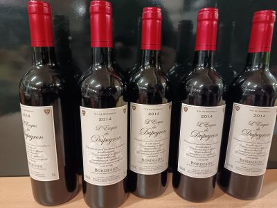 six bouteilles de vin rouge sont alignées sur une table
