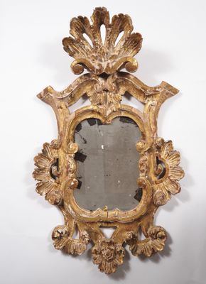 un miroir ancien doré orné d'un motif décoratif, accroché au mur