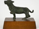 bronze statue of a dog on a wooden base on a white background