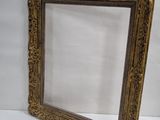 an old picture frame sitting on top of a table next to a white wall