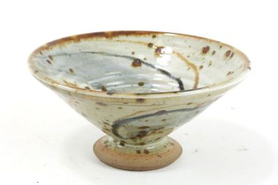 a white and brown bowl on a stand on a white surface